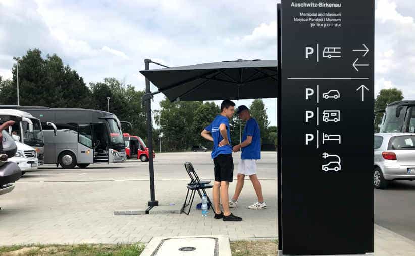 The main Auschwitz parking lot with young guards in blue t-shirts