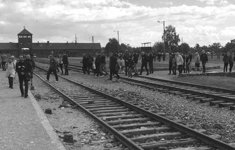 Visitors walking over the train tracks at Auschwitz II Birkenau unloading ramp