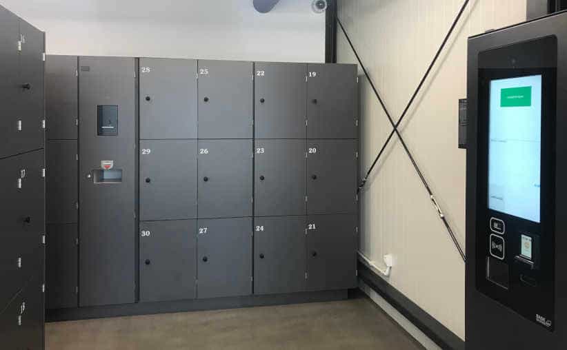 Luggage storage with grey lockers and a payment machine at Auschwitz I main parking lot.
