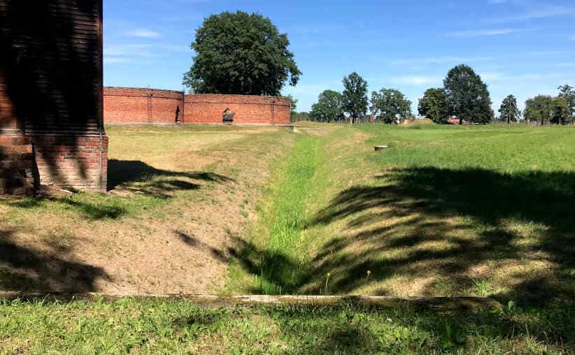 The royal ditch, part of a guard tower and sewage buildings nearby Sauna at Auschwitz-II-Birkenau.