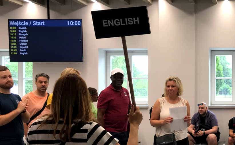 A guide with a language board in the Auschwitz I reception hallway